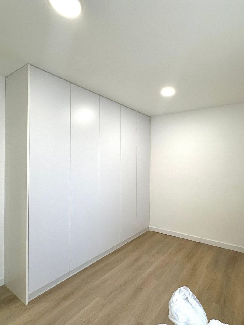 Dormitorio reformado en Vigo con armario empotrado blanco hasta el techo y suelo laminado