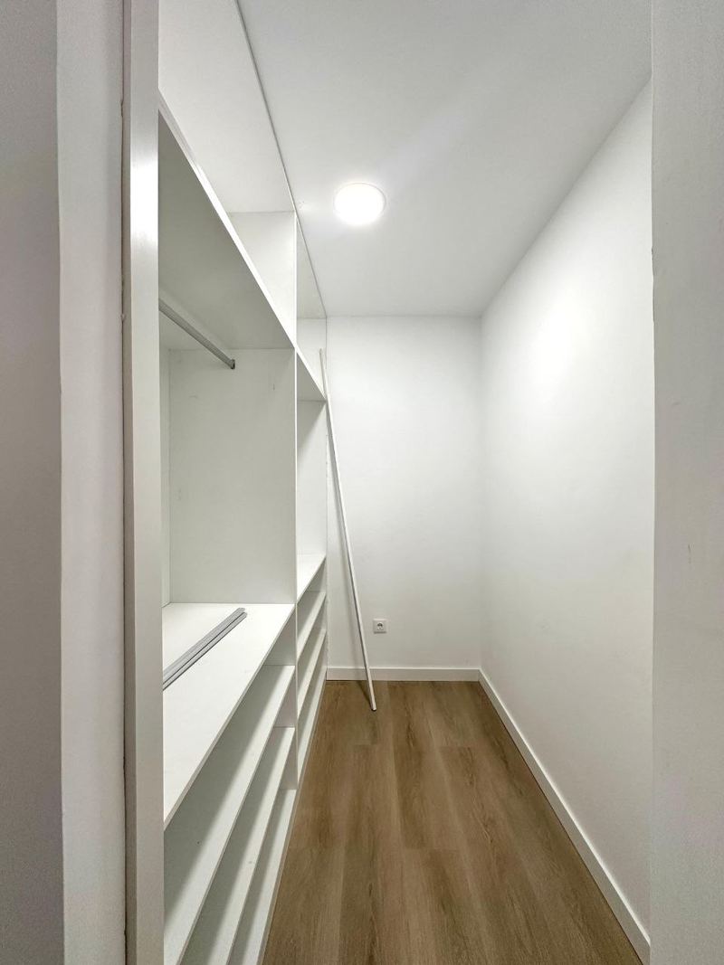 Vestidor a medida en un piso reformado de Vigo con baldas y barras abiertas en blanco